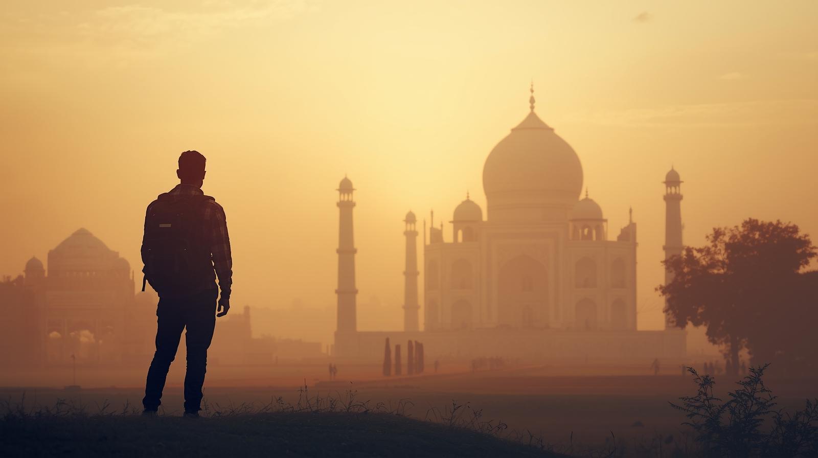 Traveler admiring the Taj Mahal at sunrise in India, representing exploration and world travel inspiration.